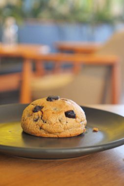 Bir kafede bir kurabiye tabakta oturur. Arka plan masa ve sandalyeleri gösteriyor..