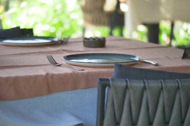 Bir yemek masası misafirler için tabak ve çatal bıçak ile hazırlanır..