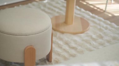 Yuvarlak tabure ve ahşap masa ışıkla dolu parlak bir odada oturur..