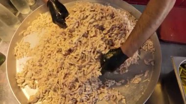 İşçiler ticari bir mutfakta büyük miktarda et hazırlıyorlar..