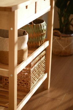 Ahşap rafta örülmüş sepetler var. Parlak kapalı bir alanda güneş ışığı var..