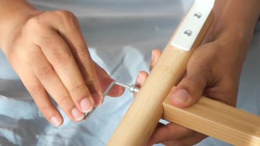 Eller, atölye içindeki aletleri ve parçaları kullanarak ahşap bir çerçeve oluşturmaya çalışır..