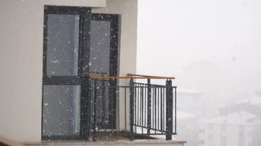 Şehirdeki boş bir balkona şiddetli kar yağar..