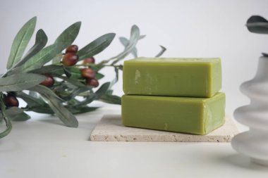 Basit bir yüzeyde yeşil sabun ve zeytin bitkisi düzenleme.