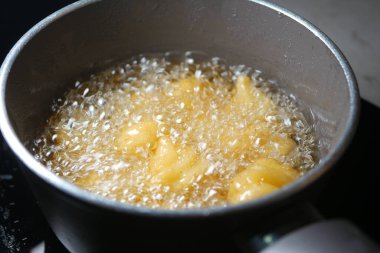 Patatesler, mutfak sobasında kızgın yağda kızartılıyor..