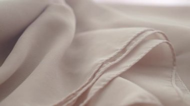 Kumaş kıvrımlarla ve ışıkta görünen dokularla nazikçe uzanır..