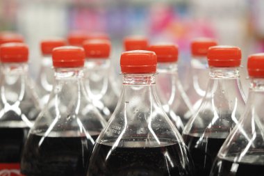 Birkaç şişe turuncu kapaklı soda bir mağazanın rafında duruyor..