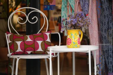 Bir sandalye ve masa bir vazo çiçeği bir mağazanın vitrininde tutar..