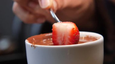 Bir el taze çileği erimiş çikolataya batırır..