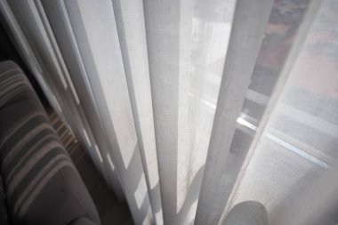 Güneş ışığı, oturma odasındaki perdelerin arasından süzülür..