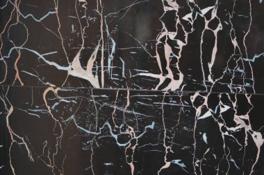 Yüzeyde taşta siyah, beyaz ve pembe desenler var..