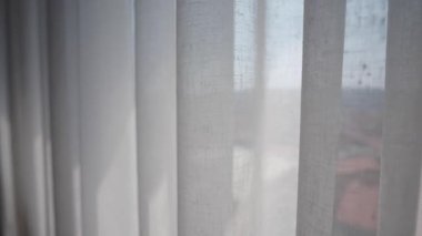 Dışarıda sakin bir manzarası olan bir odada, perdelerin arasından ışık süzüyor..