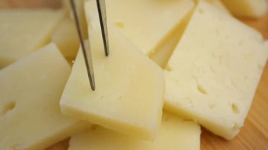 İnsanlar peynir tadıyor ve parçaları kesmek için aletler kullanıyorlar..