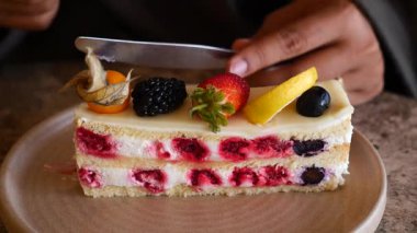 Biri pastayı krema ve taze böğürtlenlerle dilimliyor..