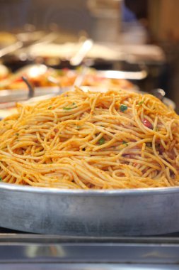 Restoran mutfağında müşterileri bekleyen büyük bir tabak spagetti..