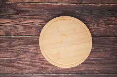 Yuvarlak ahşap bir tabak tahta bir masa yüzeyine yerleştirilir..