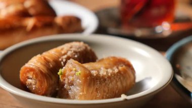 Baklava, yakınlardaki diğer hamur işleriyle birlikte beyaz bir tabağa konur..