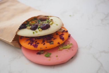 Masada kağıt bir torbaya konmuş üç çeşit şeker var..