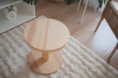 Yuvarlak ahşap bir masa oturma odasındaki yumuşak bir halıya oturur..