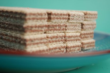 Gofretler yeşil arka planı olan mavi bir tabakta güzelce istiflenmiştir..