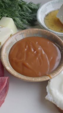 Taze sebze ve otların yanında bir kase sos..