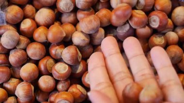 Bir insan kalabalık bir pazarda büyük bir kazıktan fındık toplar..