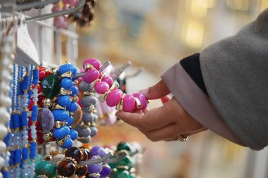 Markette mücevher ararken bilezik tutan bir kişi..