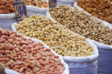 Bags filled with different kinds of nuts are arranged at a market stall.