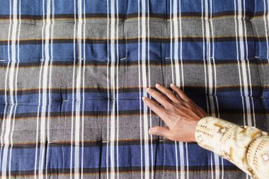 Bir el, bir pazar ortamındaki renkli dokuma kumaşa dayanır..