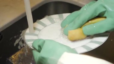 Eller tabağı yıkıyor ve lavaboda bir sünger var..