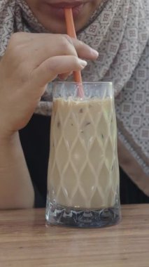 Gün boyunca kafede otururken buzlu kahveyi yudumlayan biri..