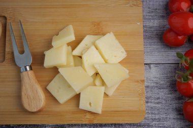 Peynir kalıpları kiraz domateslerinin yanındaki tahta bir tahtada kesilir..