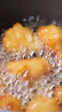 Hamur topları kızgın yağda kızarıyor, tavada kaynıyor ve pişiyor..