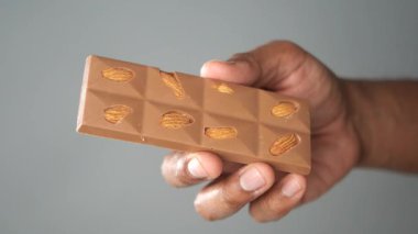 Birisi elinde fındıkla çikolata tutuyor..