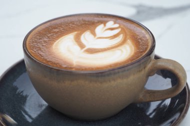 Basit bir masa yüzeyine köpük resimli bir fincan kahve..