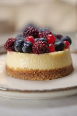 Taze böğürtlenli bir cheesecake tatlısı beyaz bir tabakta duruyor..