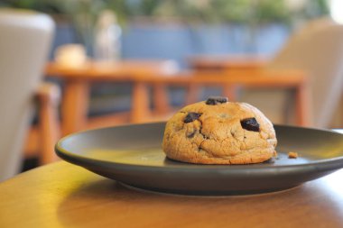 Kurabiye, bir kafedeki ahşap bir masada siyah bir tabakta oturur..