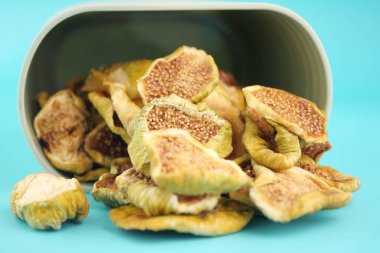 Kurumuş meyve parçaları mavi üzerine devrilmiş bir konteynerin yanına saçılmış..