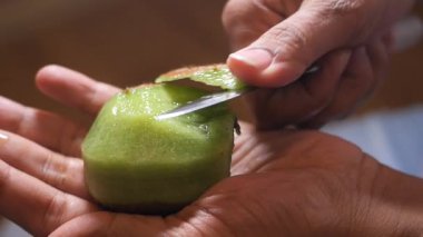 Mutfakta bıçakla kivi meyvesi soyuyorsun..