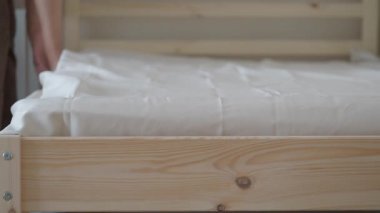 Birisi yatak odasında temiz çarşaf seriyor..