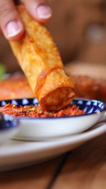 Bir insan çıtır böreği evdeki aromalı sosa batırır..