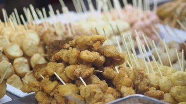 İnsanlar akşamları kalabalık bir gıda pazarında kızarmış tavuk şiş yemeyi severler..