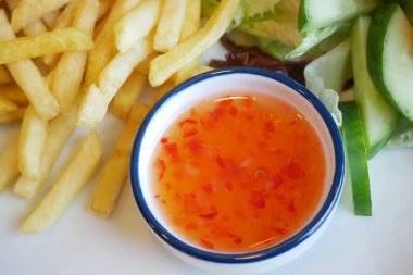 Kızartmalar taze sebzeler ve bir sos kasesiyle bir tabağa konur..