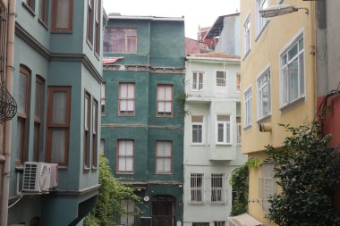 Buildings in different colors line a narrow street with greenery.