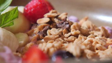 Meyve ve tahıl gevreğiyle dolu kahvaltı kâsesine yakından bak..