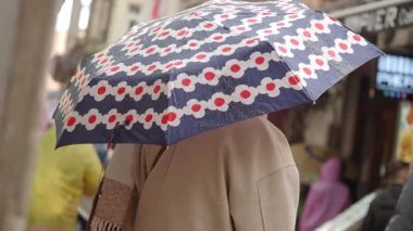 Yağmurlu bir günde bir insan renkli bir şemsiye altında yürür..