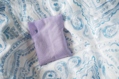 Bir lavanta kesesi mavi beyaz kumaşa dayanır..