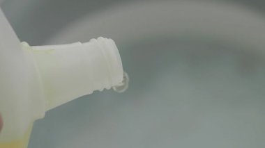 Birisi evde kullanmak için konteynıra temizlik çözeltisi döker..