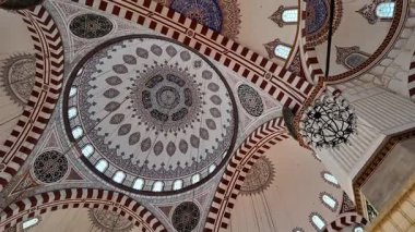 Visitors admire intricate patterns and details on the mosque ceiling.