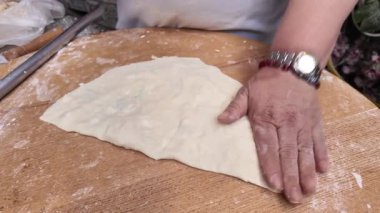 Bir insan mutfakta ahşap bir yüzey üzerinde hamur hazırlıyor..